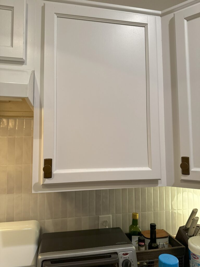Kitchen cabinets painted white with new brass knobs! Featuring our new backsplash.